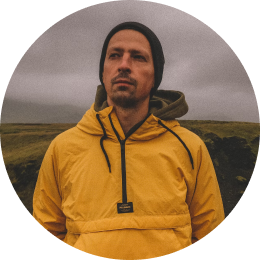 Viajero con una chaqueta de lluvia amarilla, de pie en el paisaje sombrío y nublado de Islandia.