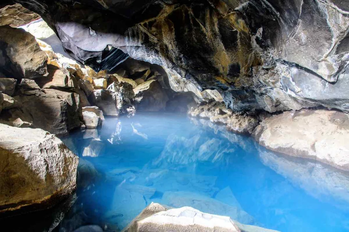 Interior de la cueva de Grjotagja con aguas termales en azul intenso