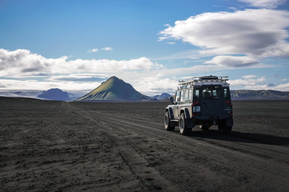 Jeep atravesando un paisaje volcánico con una impresionante montaña cónica detrás