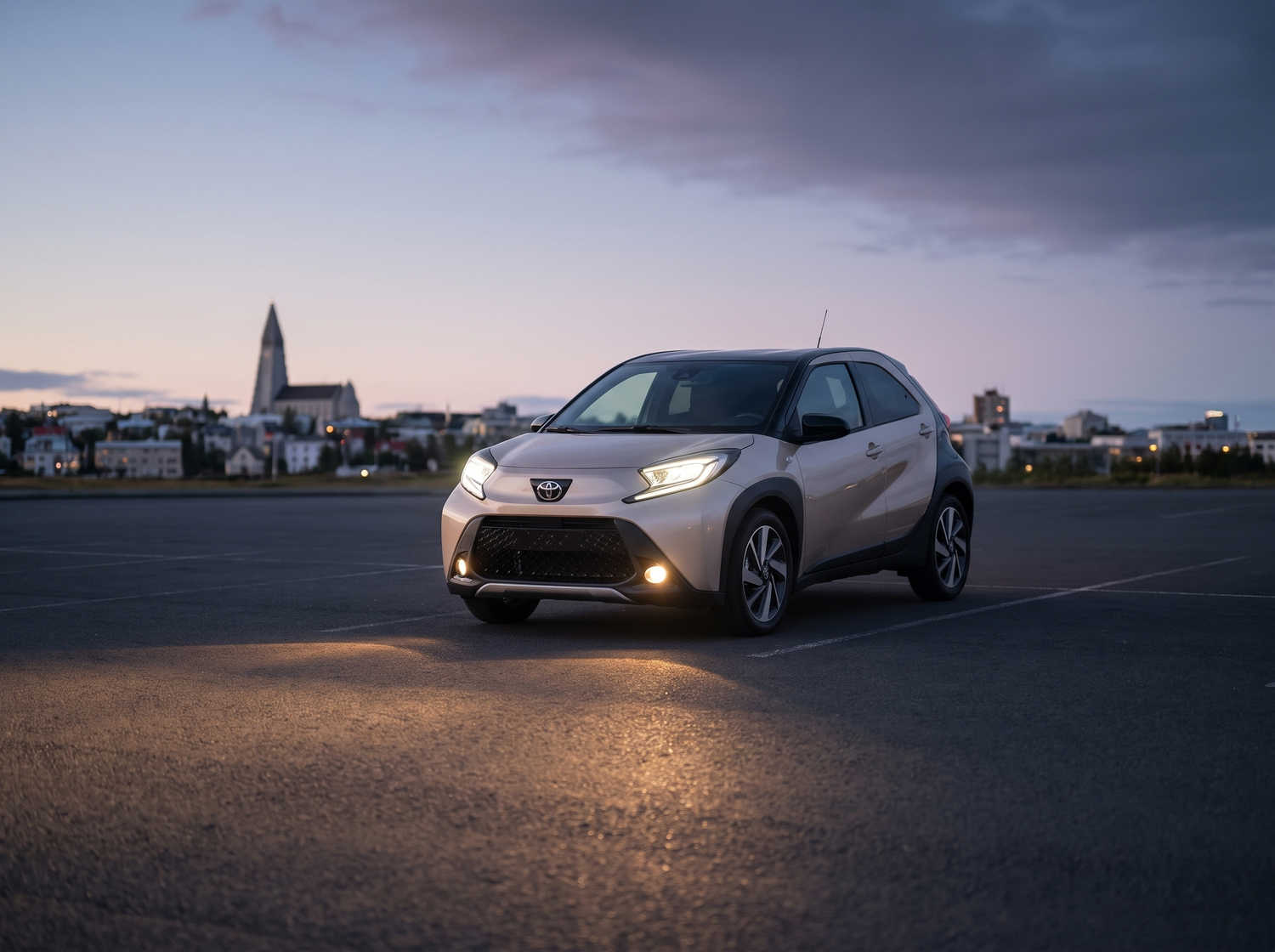 Toyota Aygo naranja vibrante con transmisión automática, ideal para 4 pasajeros, compacto y eficiente para recorrer ciudades islandesas.
