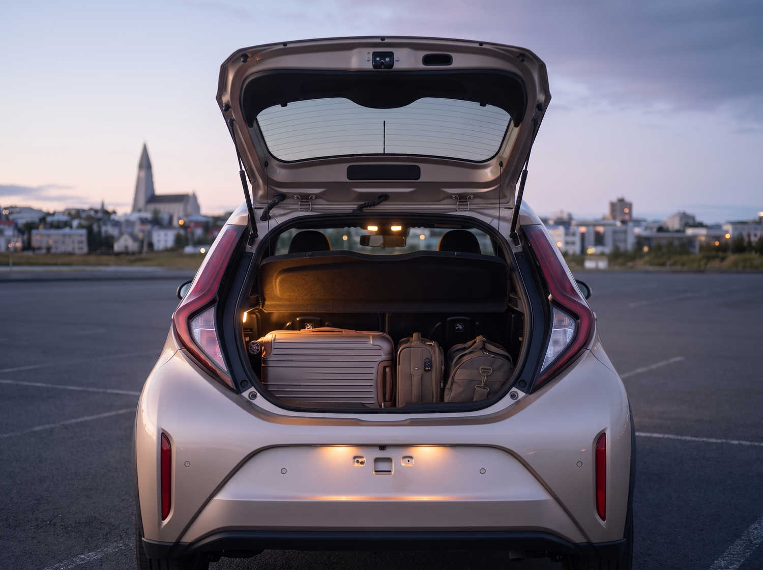 Toyota Aygo naranja vibrante con transmisión automática, ideal para 4 pasajeros, compacto y eficiente para recorrer ciudades islandesas.