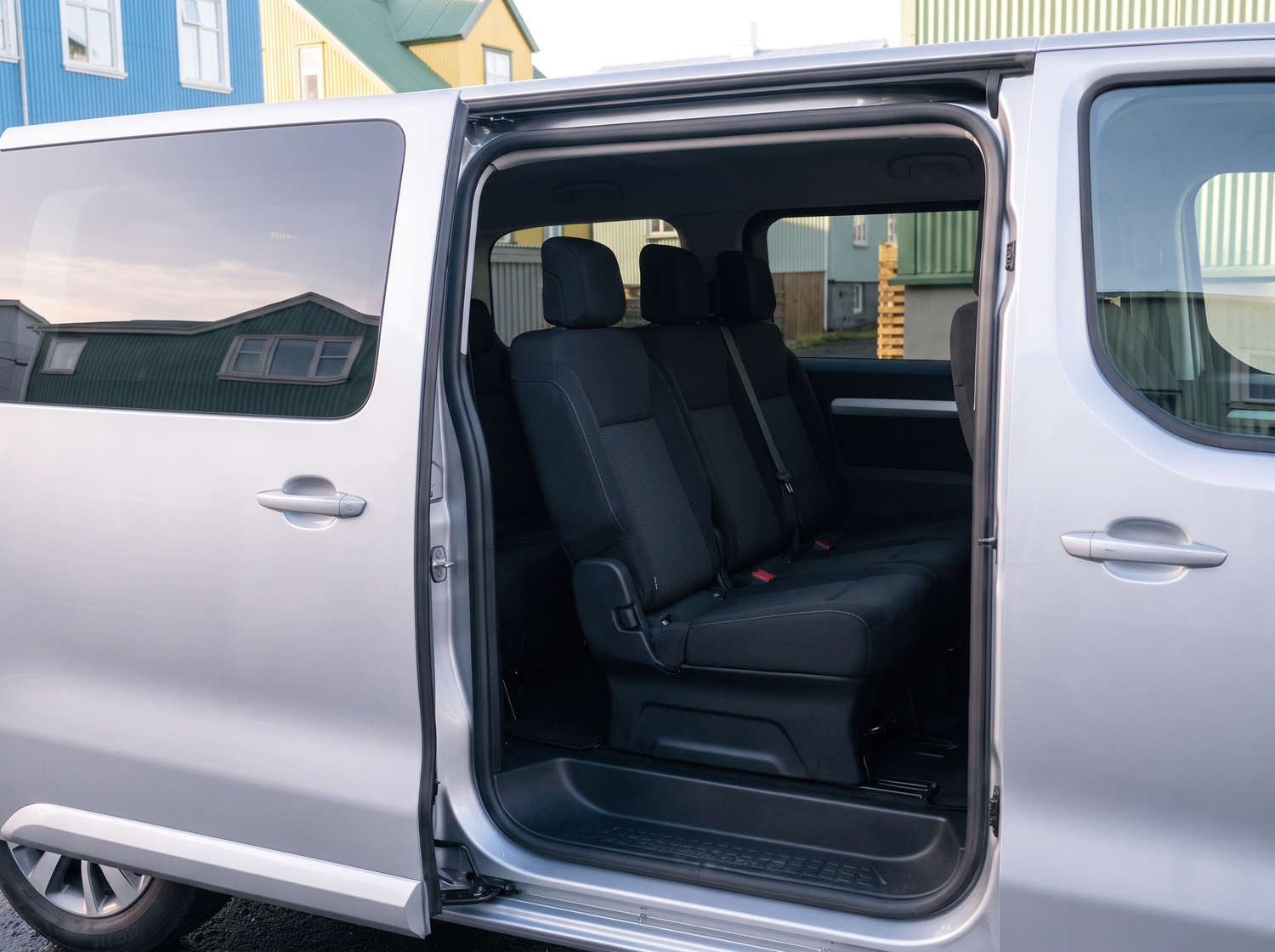Toyota Proace plateada de 9 plazas con transmisión automática, GPS, Bluetooth, asientos calefactables y cargador USB; ideal para viajes en grupo por Islandia.