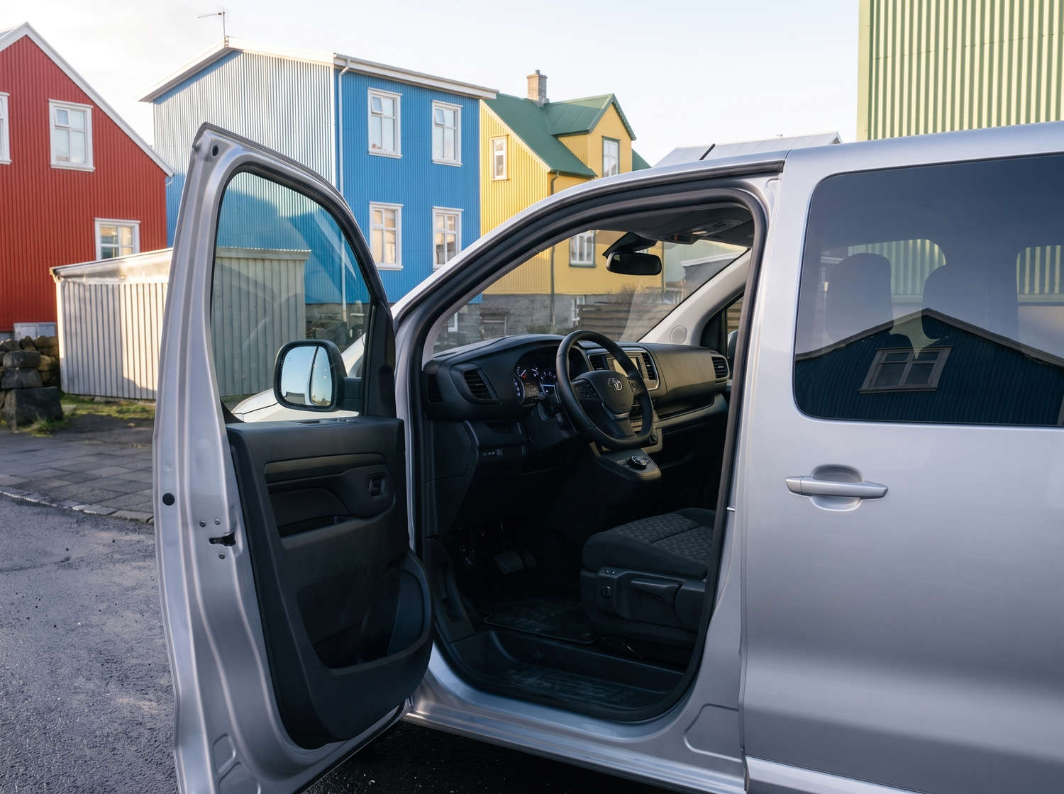 Toyota Proace plateada de 9 plazas con transmisión automática, GPS, Bluetooth, asientos calefactables y cargador USB; ideal para viajes en grupo por Islandia.