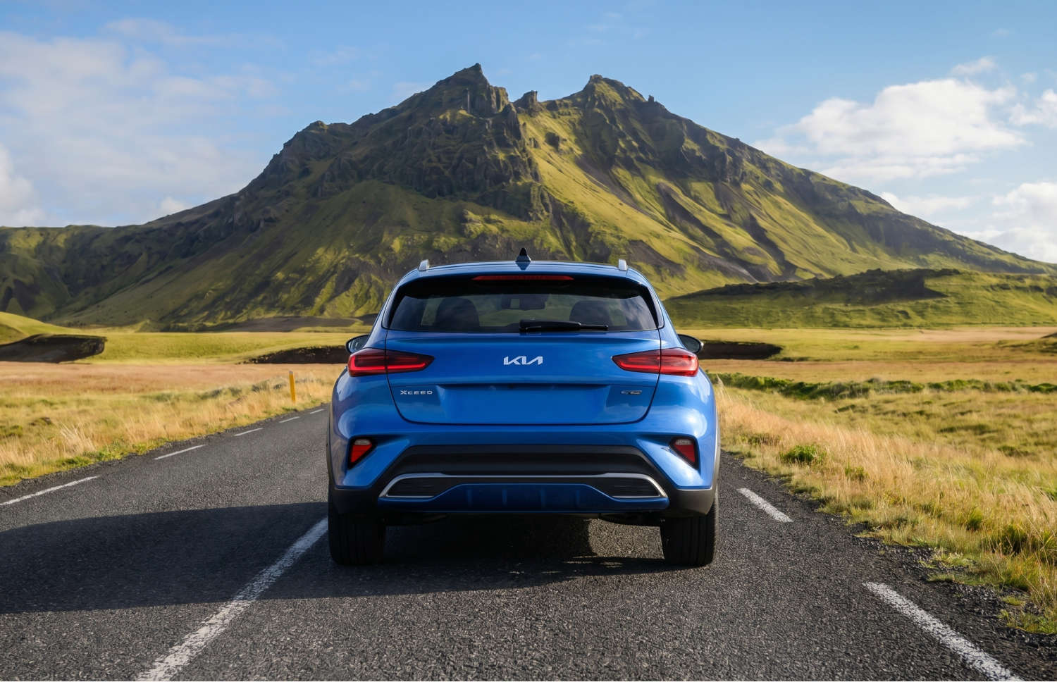 Kia XCeed crossover amarillo brillante con transmisión automática, GPS, cámara de reversa y asientos calefactables; capacidad para 5 personas y 2 maletas, ideal para viajar por Islandia.