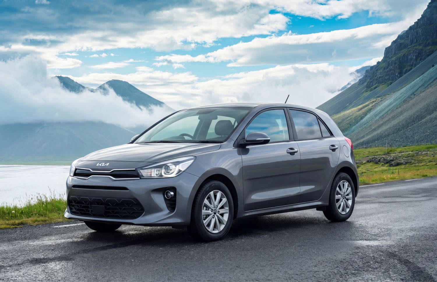 Kia Rio azul con transmisión manual, GPS, cámara de reversa y espacio para 5 pasajeros y 2 maletas, ideal para viajes por carretera en Islandia.