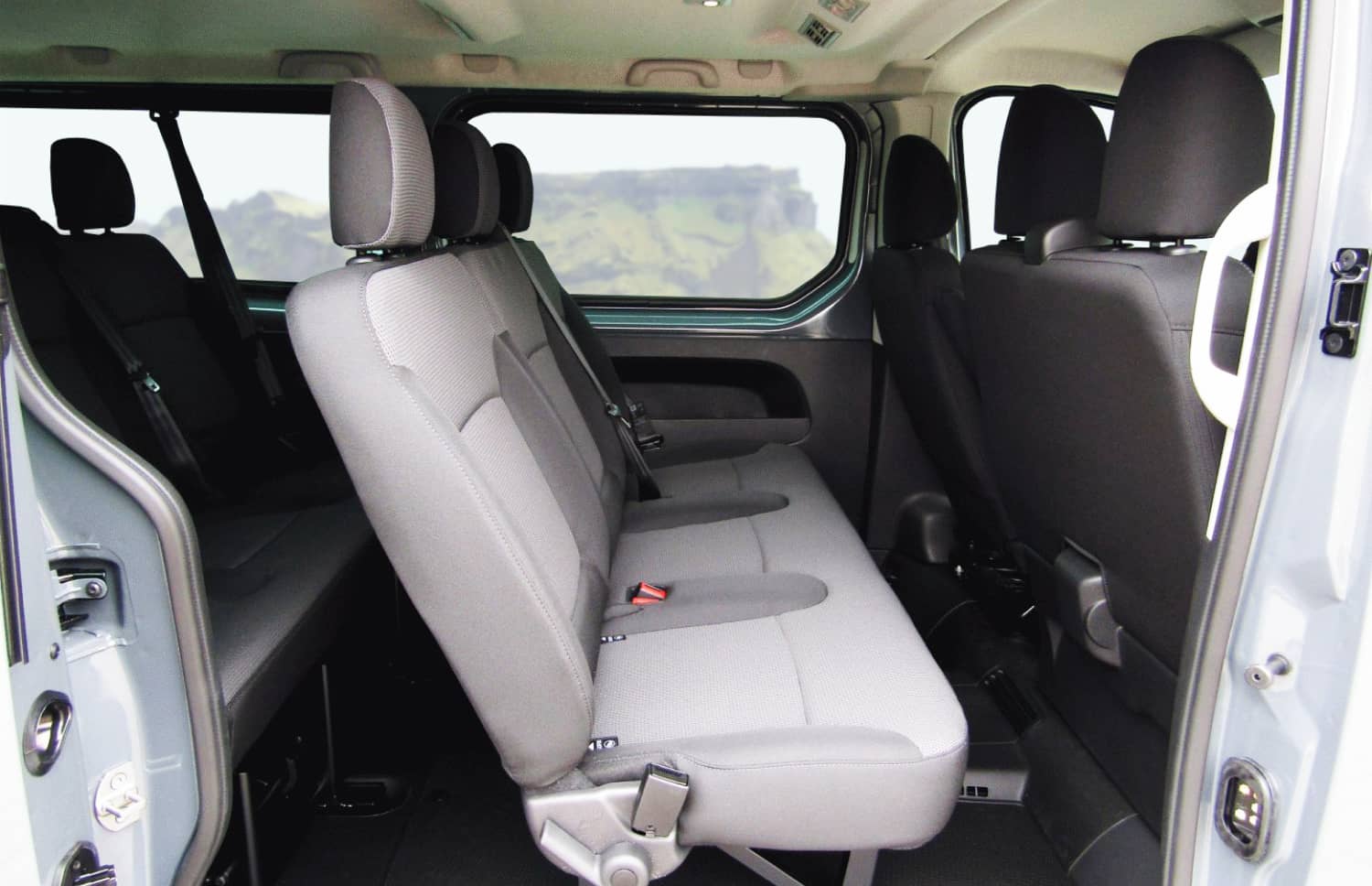 Renault Trafic roja de 9 plazas con transmisión manual, asientos calefactables, Bluetooth y cargador USB; ideal para viajes en grupo por Islandia.