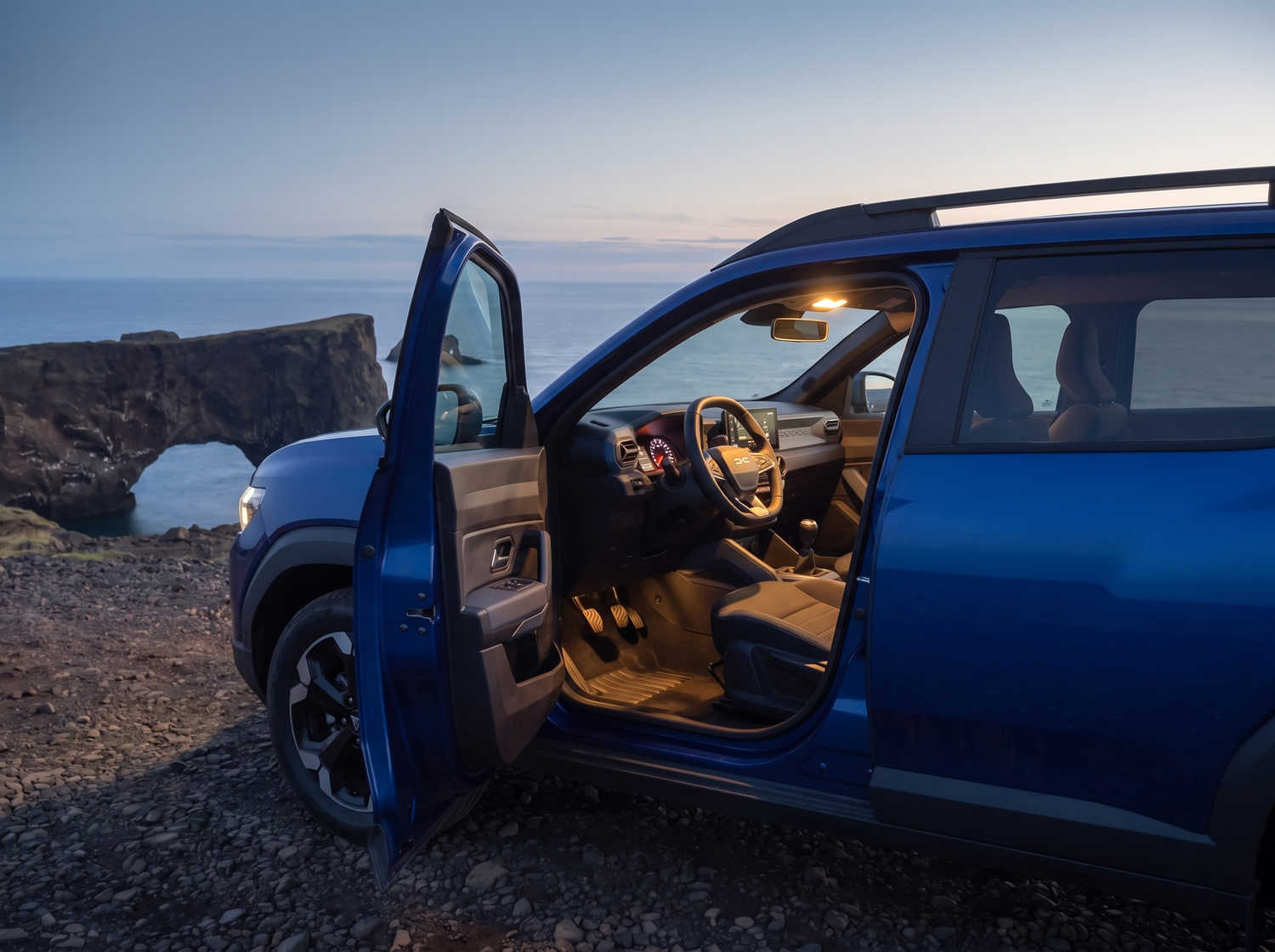 Dacia Bigster azul con transmisión manual y tracción en las cuatro ruedas, capacidad para 5 personas y 4 maletas, diseñado para las carreteras difíciles de Islandia con total comodidad.